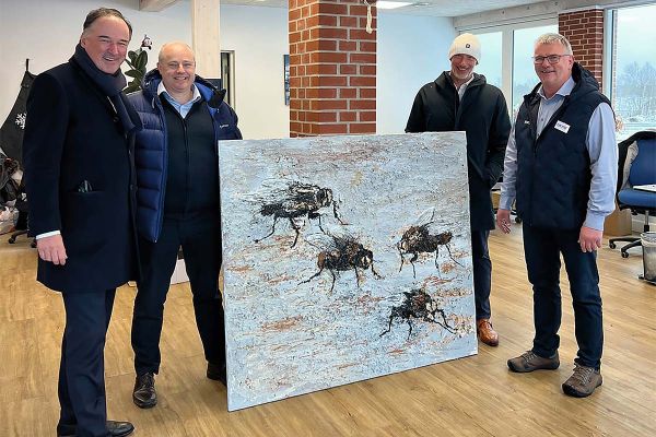 Ein Kunstwerk zur Eröffnung der Insektenzuchtfarm: Big Dutchman CEO Dr. Frank Hiller, Leo Østergaard, CEO der Big Dutchman-Tochtergesellschaft Skov A/S, und Big Dutchman-Vorstandsmitglied Robert-Jan Lousberg überreichten ein dekoratives Gastgeschenk an Enorm Biofactory-Mitbegründer und CEO Carsten Lind Pedersen (v.l.n.r.)